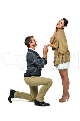 Man proposing woman while kneeling and holding hands
