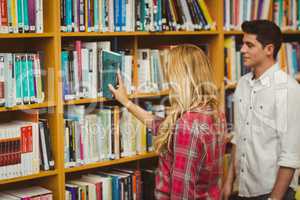 Smiling female student picking book