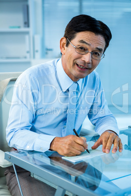 Smiling asian businessman signing document