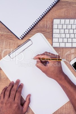 Businessman writing on notebook by computer keyboard