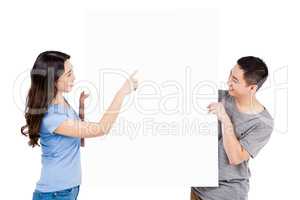 Happy young couple holding blank billboard