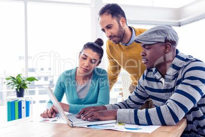 Business man using laptop with colleagues in background