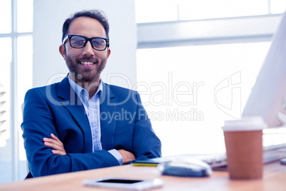 Portrait of happy businessman with arms crossed in office