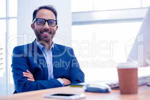 Portrait of happy businessman with arms crossed in office