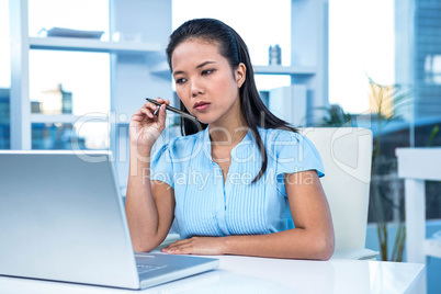 Thoughtful young businesswoman sitting at her desk