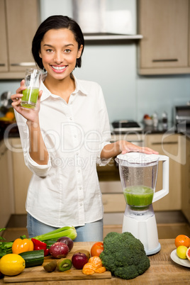 Smiling brunette holding glass of smoothie