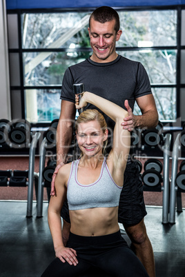 Fit woman doing dumbbells exercise with trainer