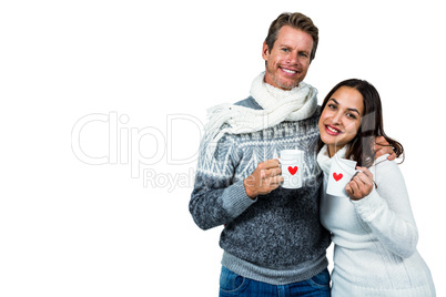 Festive couple smiling and holding mugs