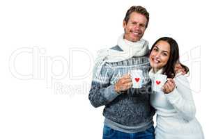 Festive couple smiling and holding mugs