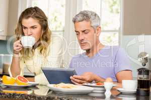 Happy couple using tablet and having breakfast