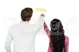 Rear view of couple holding paint roller