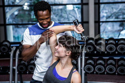 Fit woman doing dumbbells exercise with trainer