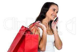 Smiling woman holding shopping bagsand using smartphone