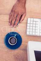 Businessman using mouse by coffee cup while working