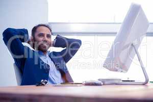 Businessman relaxing with hands behind head in office
