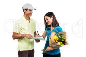 Happy woman signing on clipboard while receiving bouquet