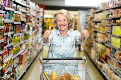 Smiling senior woman with cart showing thumbs up Smiling senior woman with cart showing thumbs up