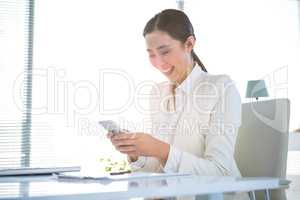 Smiling businesswoman texting on her phone