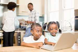 Siblings using laptop in kitchen