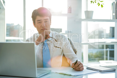 Thoughtful asian businessman at his desk