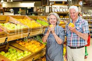 Smiling senior couple holding oranges