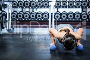 Fit woman doing push ups with dumbbells