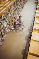 Student in wheelchair picking a book from shelf