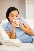 Peaceful brunette drinking by white cup