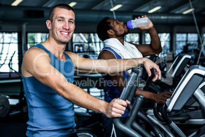 Smiling man using elliptical machine