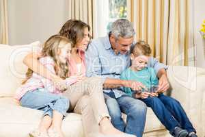 Happy family using phone on sofa