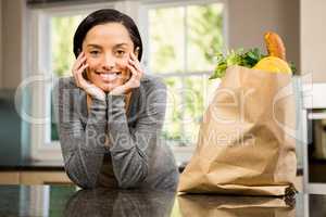 Smiling brunette with  grocery bag on counter