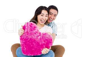 Portrait of cheerful young couple with heart shape pillow