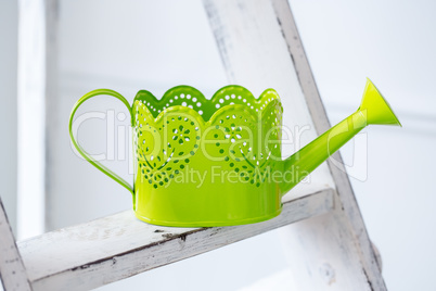Green watering can on desk