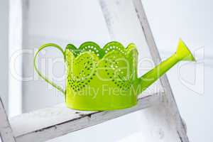 Green watering can on desk