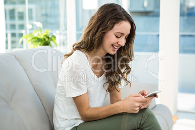 Happy woman texting on sofa