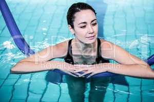 Fit smiling woman swimming with a foam roller