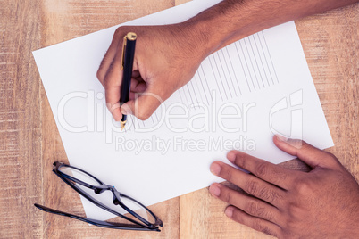 Cropped hand of businessman writing on paper