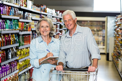 Smiling senior couple with cart checking list