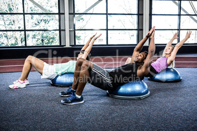 Fit people doing exercise with bosu ball