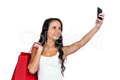 Smiling woman holding shopping bags taking selfie