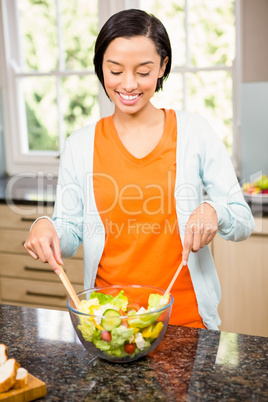 Smiling brunette preparing salad