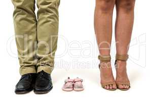 Low section of man and woman amidst baby shoes