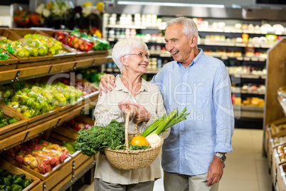 Smiling senior couple holding basket with vegetables