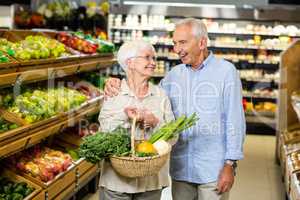 Smiling senior couple holding basket with vegetables