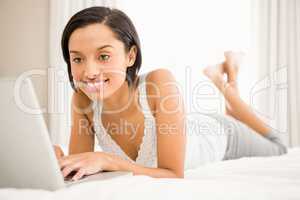 Smiling brunette using laptop