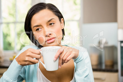 Upset brunette holding white cup