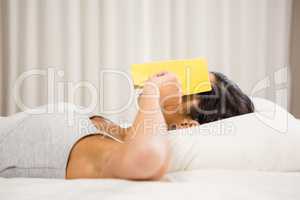 Brunette with book on face