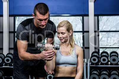 Fit woman doing dumbbells exercise with trainer