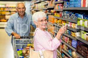 Senior woman taking a picture of product on shelf