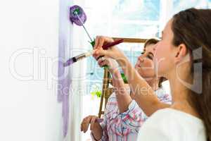 Mother and daughter focused on painting